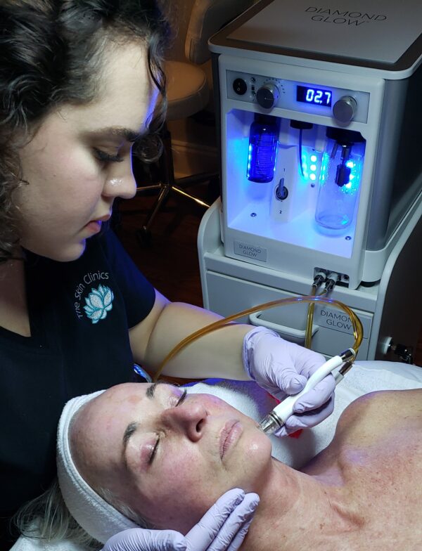 one of The Skin Clinics' estheticians giving a client a diamond glow facial treatment